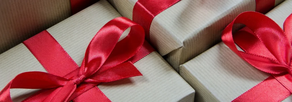 Geschenkverpackungen in braunem Papier mit roten Schleifen, ideal für verschiedene Anlässe wie Geburtstage oder Feiertage.