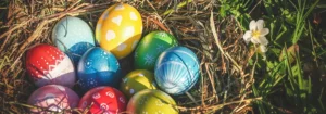 Bunte Ostereier in einem Nest aus Heu, umgeben von grünem Gras.