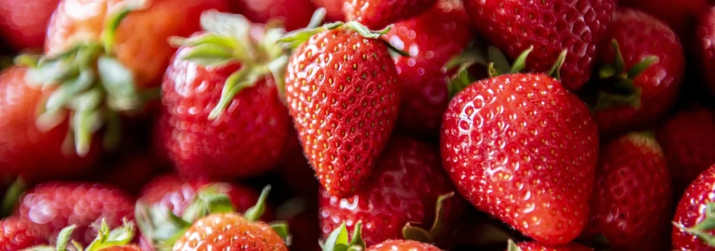 Eine Ansammlung von frischen, roten Erdbeeren mit grünen Blättern.