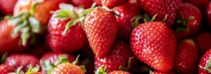 Eine Ansammlung von frischen, roten Erdbeeren mit grünen Blättern.