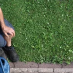 Mann, der sich mit Gartenwerkzeugen und einem Eimer auf dem Boden beschäftigt.