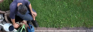 Mann, der sich mit Gartenwerkzeugen und einem Eimer auf dem Boden beschäftigt.