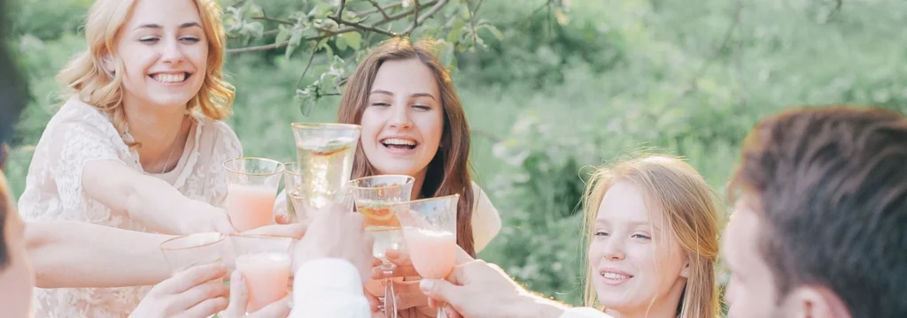 Sechs Personen stoßen mit Gläsern an, während sie lächeln und zusammen feiern.