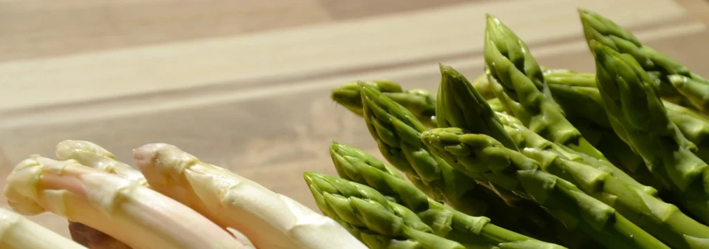 Weißer und grüner Spargel auf einem Holzbrett, mit frischen, knackigen Spitzen.